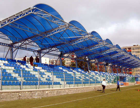 Obloukové zastřešení tribuny městského stadionu.